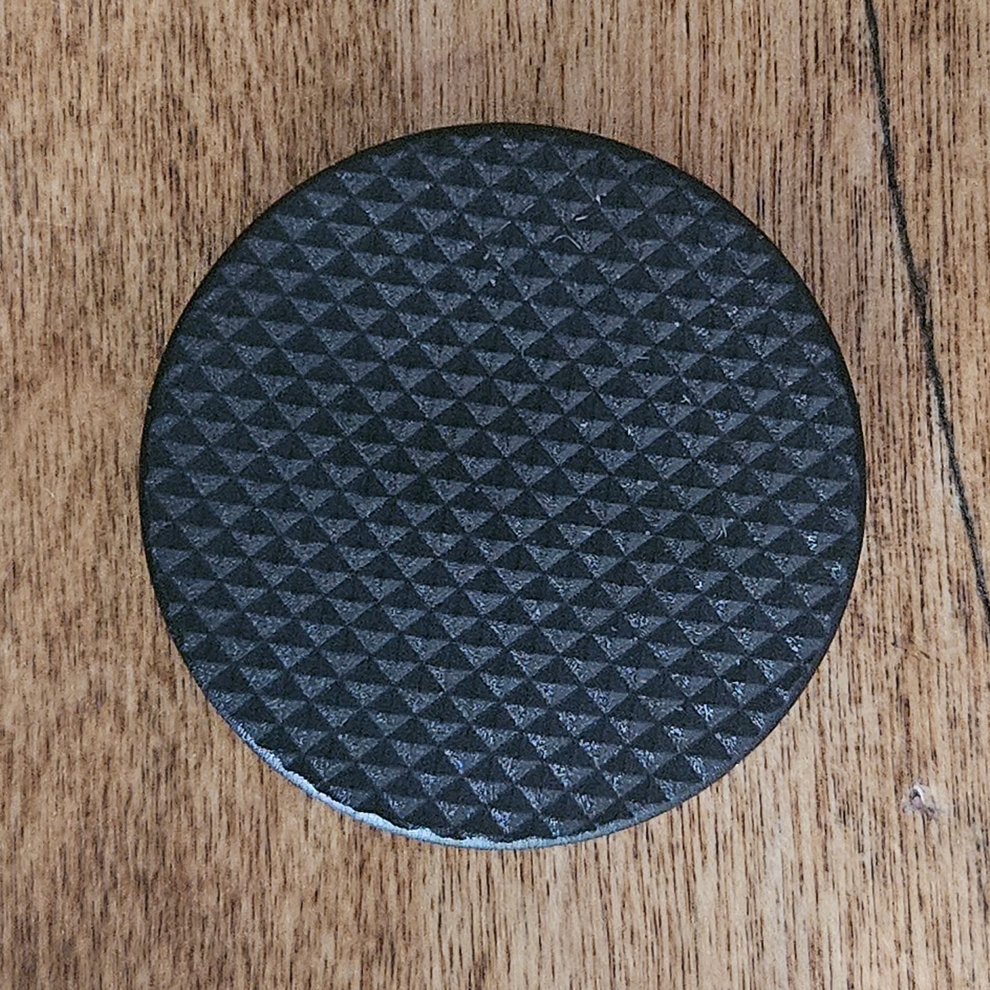 Black textured PopGrip addon for Quadlock Rokform adapters on wooden surface