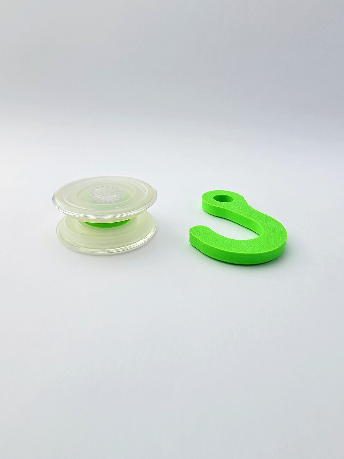 Clear PopSocket Popgrip coupler with green hook accessory on white background