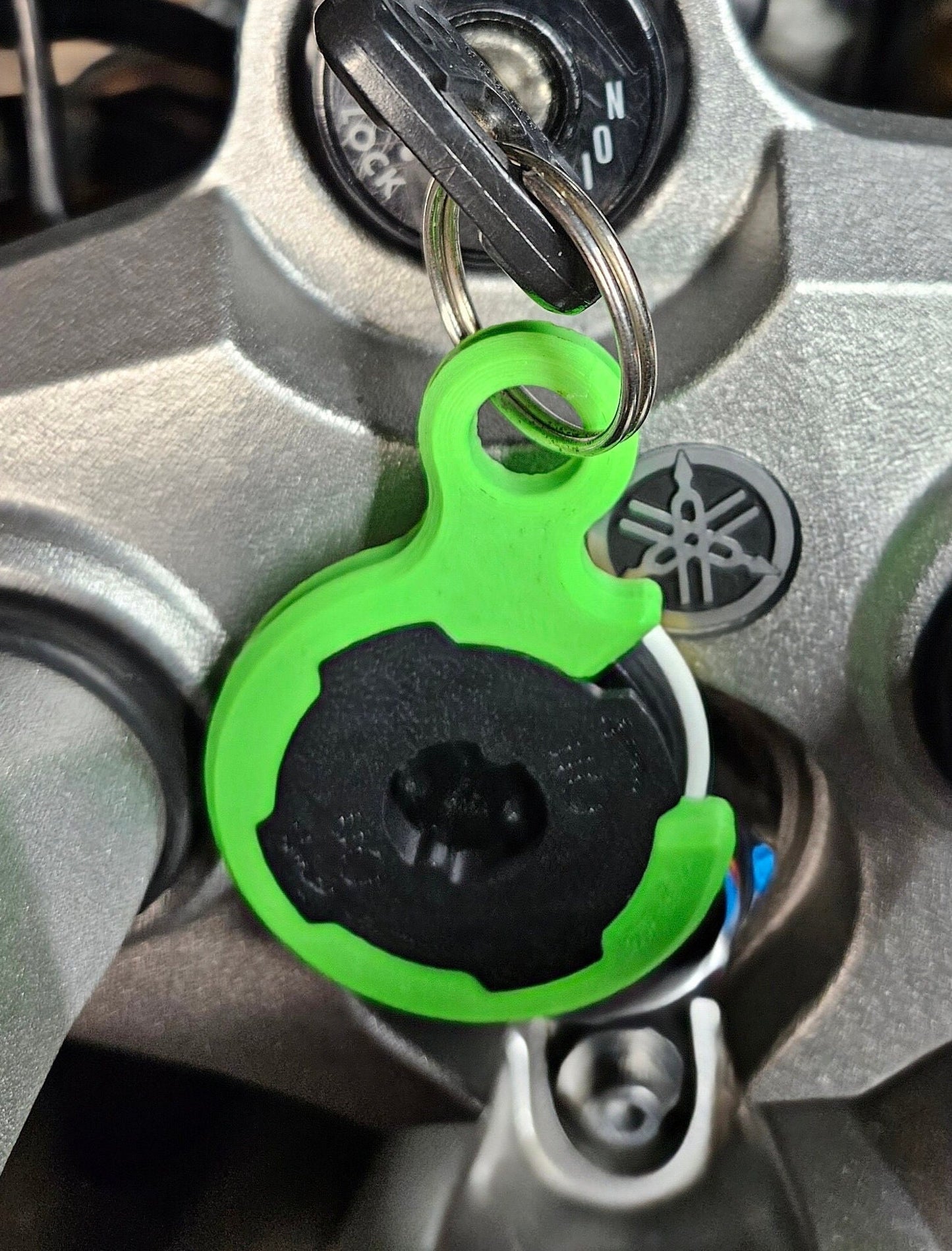Green Quadlock PopSocket adapter keychain attached to keys on a motorcycle ignition