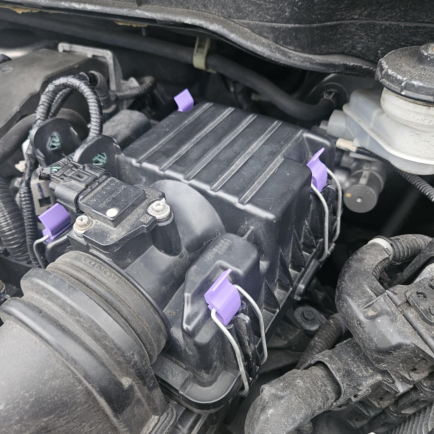3D printed Honda air cleaner clip installed on black engine air intake housing in car engine bay
