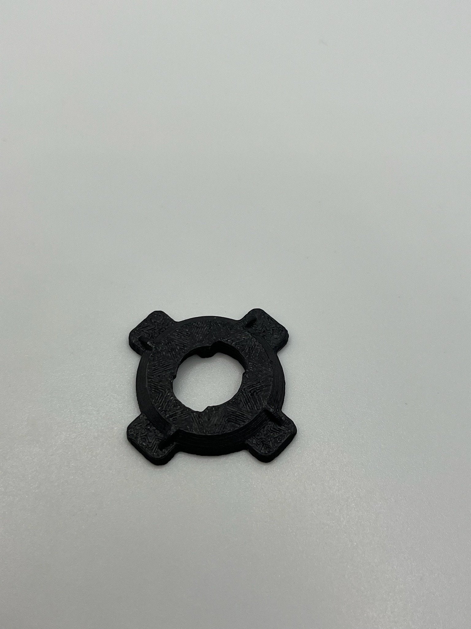 Black Rokform PopSocket adapter with four extended tabs on a white background